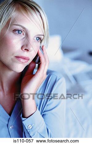 Stock Photo - Woman sitting on bed with cellphone. Fotosearch