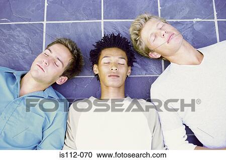 Stock Image - Men lying down on tiles. Fotosearch
