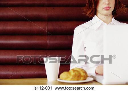 Stock Image - Woman having breakfast and working. Fotosearch