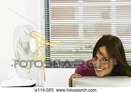 Businesswoman cooled by fan in office View Large Photo Image Stock Photography - Businesswoman cooled by fan in office. Fotosearch