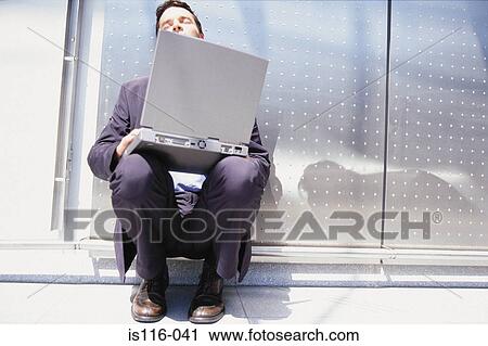 Stock Image - Businessman with computer sitting in the sun. Fotosearch