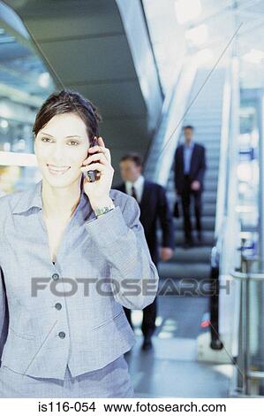 Picture - Businesswoman with cellphone at airport . Fotosearch