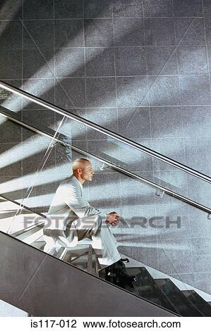 Stock Image - Businessman sitting on modern stairway. Fotosearch