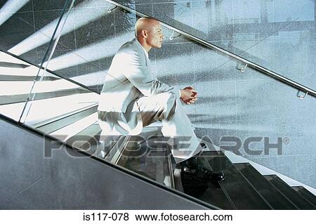 Businessman sitting on modern stairway View Large Photo Image Stock Photo - Businessman sitting on modern stairway. Fotosearch