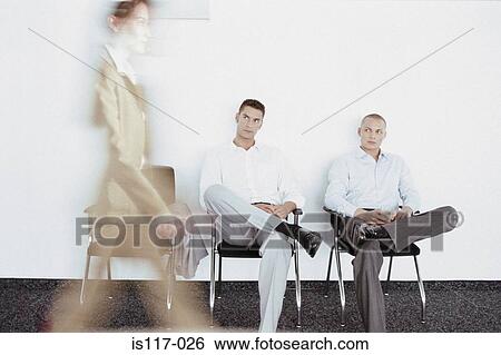 Stock Photograph - Businessmen eyeing businesswoman. Fotosearch