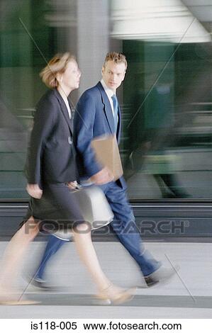 Stock Photography - Businessman and businesswoman walking briskly. Fotosearch