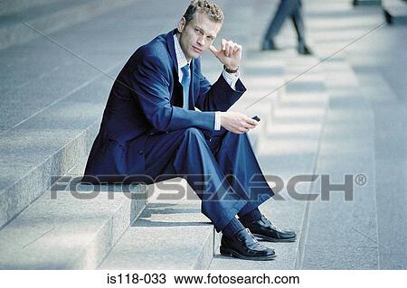 Stock Image - Businessman sitting on steps with cellphone. Fotosearch