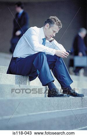Businessman sitting on steps with cellphone View Large Photo Image Stock Image - Businessman sitting on steps with cellphone. Fotosearch