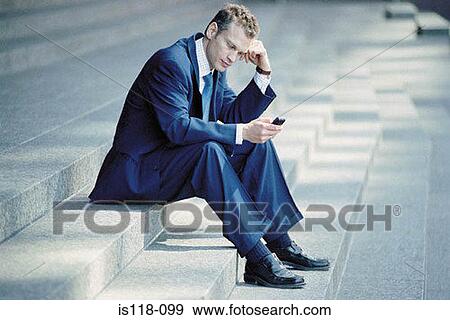 Businessman sitting on steps with cellphone View Large Photo Image Stock Photo - Businessman sitting on steps with cellphone. Fotosearch