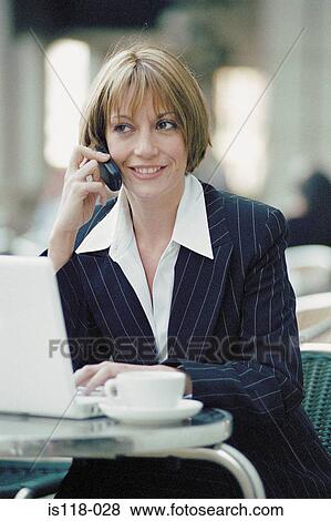 Stock Photo - Businesswoman with laptop and cellphone at a cafe. Fotosearch