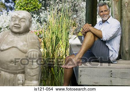 Picture - Man beside pool and buddha. Fotosearch