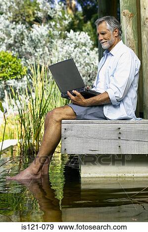 Stock Photo - Man beside pool with computer. Fotosearch