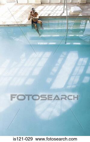 Stock Photo - Man on the edge of swimming pool. Fotosearch