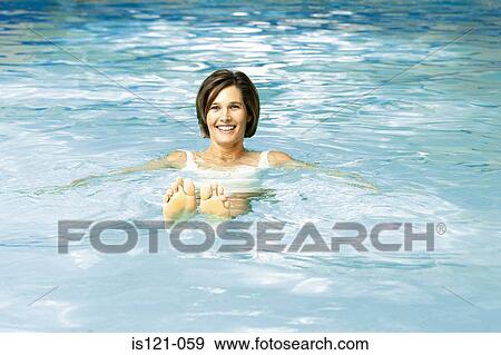 Stock Photo - Woman floating in swimming pool. Fotosearch