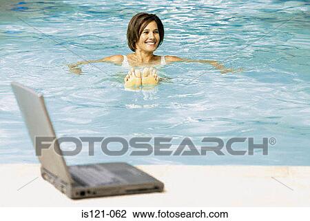 Stock Image - Woman in swimming pool with computer. Fotosearch
