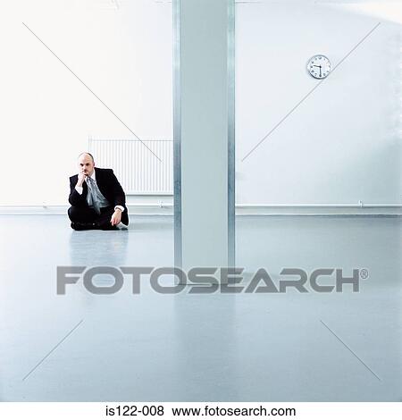 A Man seated on the floor of an open plan office View Large Photo Image Stock Photo - A Man seated on the floor of an open plan office. Fotosearch
