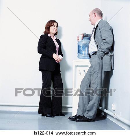 Two work colleagues having a break by the water filter View Large Photo Image Picture - Two work colleagues having a break by the water filter. Fotosearch