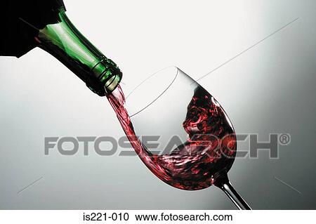 Stock Image - Red wine poured into glass. Fotosearch