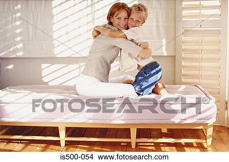 Mother and son hugging on bed View Large Photo Image Picture - Mother and son hugging on bed. Fotosearch
