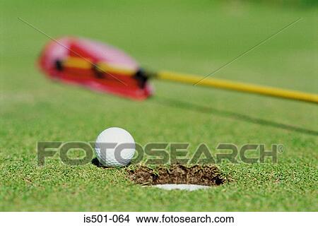 Picture - Golf ball next to hole. Fotosearch