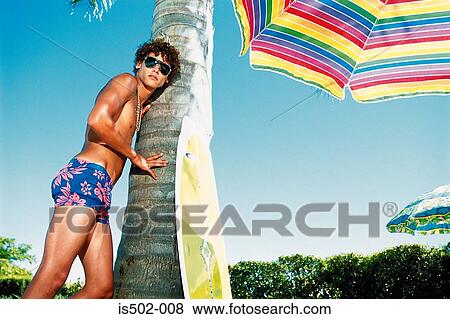 Young man leaning against a palm tree View Large Photo Image Stock Photo - Young man leaning against a palm tree. Fotosearch