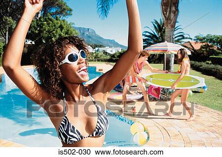 Stock Image - Young woman dancing by pool. Fotosearch