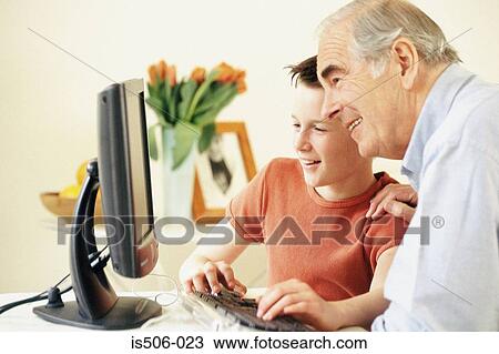 Stock Image - Grandfather and grandson using computer. Fotosearch