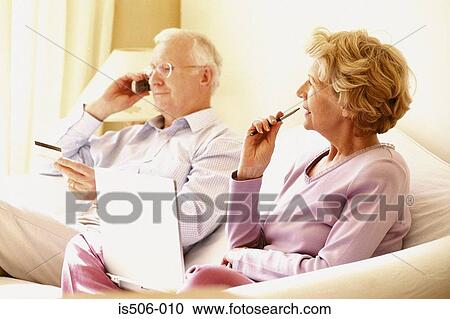 Stock Image - Man on cellphone and woman using laptop computer. Fotosearch