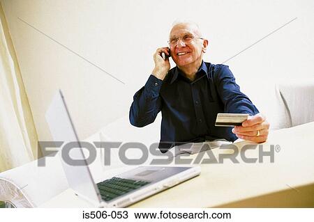 Stock Image - Man using laptop computer and cellphone. Fotosearch
