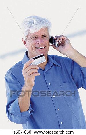 Stock Image - Man by the sea with cellphone and credit card. Fotosearch
