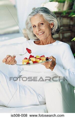 Ageing woman eating outdoors View Large Photo Image Stock Photo - Ageing woman eating outdoors. Fotosearch
