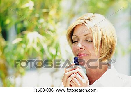 Stock Photograph - Woman smelling scent outdoors. Fotosearch