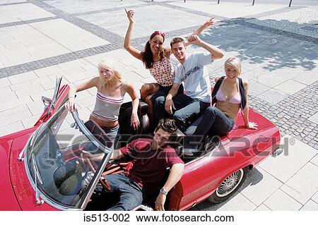 Stock Image - Group of young friends sitting on car. Fotosearch