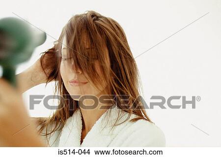Woman blow-drying hair View Large Photo Image Picture - Woman blow-drying hair. Fotosearch