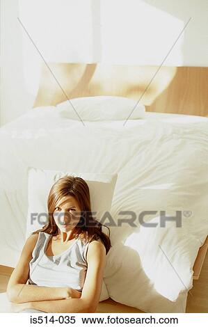 Stock Photography - Woman leaning against bed. Fotosearch