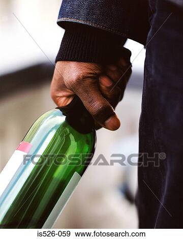 Stock Photo - A man holding an empty bottle of wine. Fotosearch