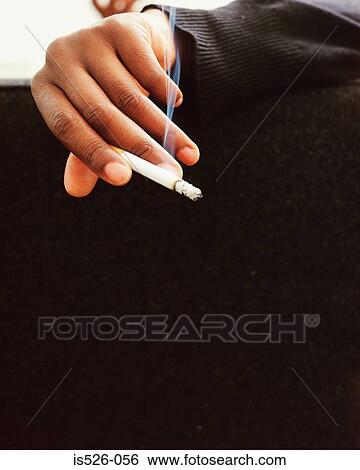 Stock Photograph - A person holding a lit cigarette. Fotosearch