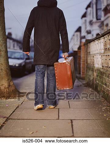 A young man carrying a leather suitcase View Large Photo Image Picture - A young man carrying a leather suitcase. Fotosearch