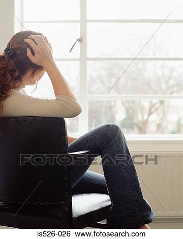 Stock Photograph - Thoughtful woman sitting on a chair. Fotosearch