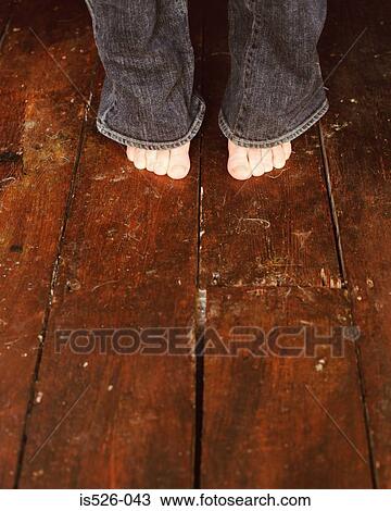 Stock Image - Woman's bare feet on wooden floor. Fotosearch