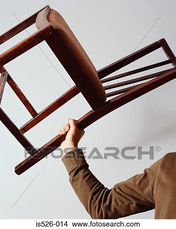 Picture - Young man holding a chair. Fotosearch