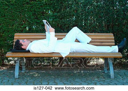 Stock Image - Man in a white suit reading. Fotosearch