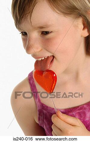 Stock Photograph - Girl licking heart shaped lollipop. Fotosearch