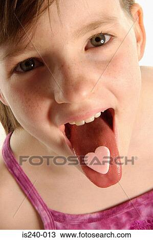 Girl with heart shaped sweet on tongue View Large Photo Image Stock Image - Girl with heart shaped sweet on tongue. Fotosearch