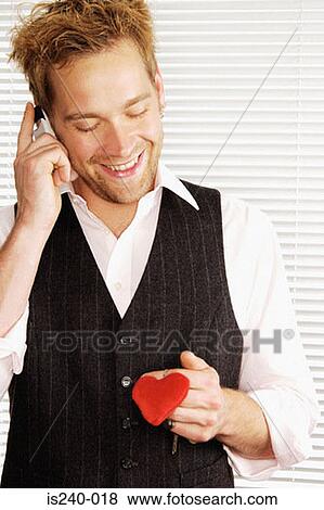 Smiling man holding heart shaped keyring View Large Photo Image Stock Photo - Smiling man holding heart shaped keyring. Fotosearch