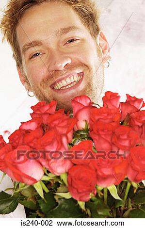 Stock Image - Smiling man holding red roses. Fotosearch