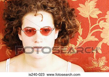 Stock Image - Woman wearing heart shaped sunglasses. Fotosearch