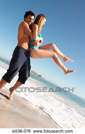 Man holding a woman on a beach View Large Photo Image Stock Photograph - Man holding a woman on a beach. Fotosearch