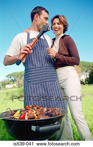 Couple cooking food on barbeque View Large Photo Image Stock Image - Couple cooking food on barbeque. Fotosearch