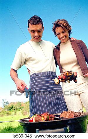Stock Photography - Couple cooking food on barbeque. Fotosearch